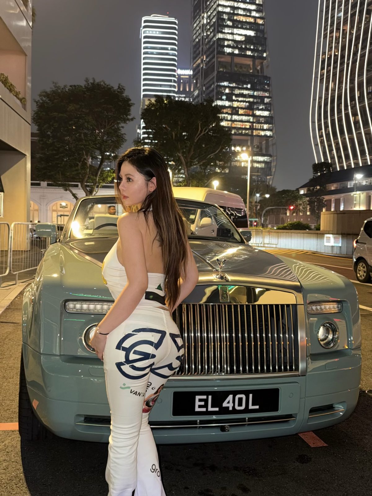 Riri in the dress by a Rolls Royce, back